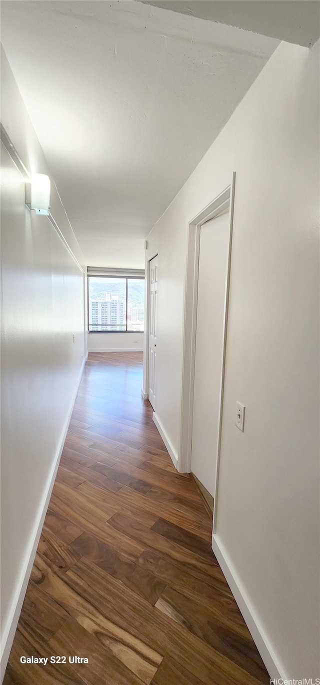 hallway featuring dark wood-type flooring and baseboards