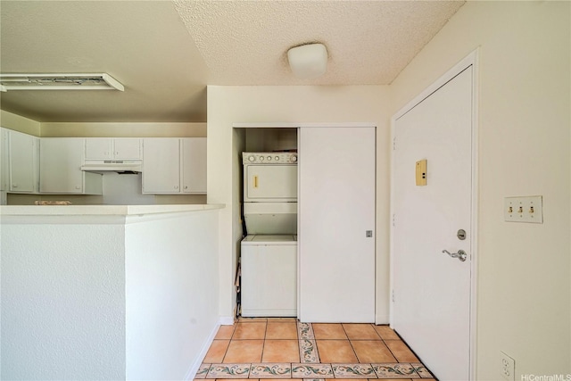 95-1059 Koolani Dr Unit 2, Mililani, HI 96789 - kitchen featuring stacked washing maching and dryer, a textured ceiling, baseboards, under cabinet range hood, and light tile patterned flooring