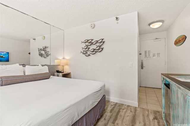 444 Kanekapolei St Unit 208, Honolulu, HI 96815 - bedroom featuring a textured ceiling, light wood-style flooring, and baseboards
