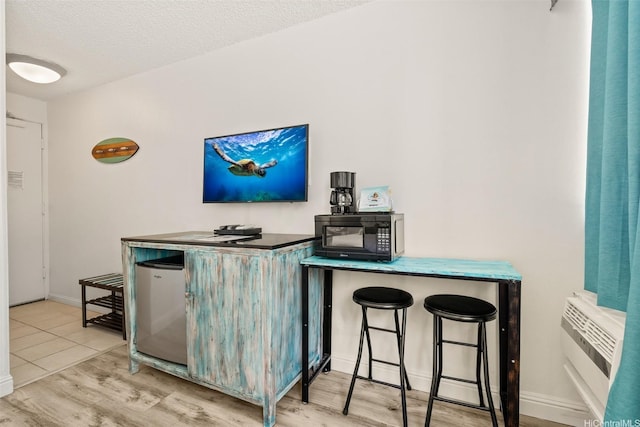 444 Kanekapolei St Unit 208, Honolulu, HI 96815 - bar featuring black microwave, wood finished floors, a wall unit AC, a textured ceiling, and baseboards