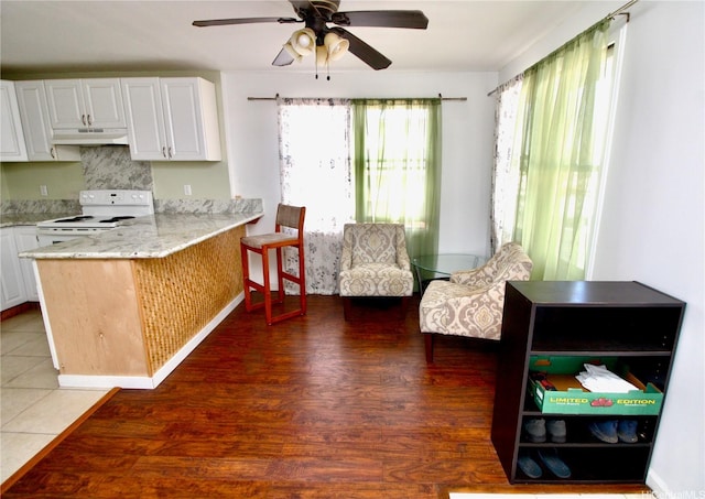 45-510 Pahia Rd, Kaneohe, HI 96744 - kitchen with under cabinet range hood, white range with electric stovetop, a ceiling fan, a peninsula, and white cabinetry