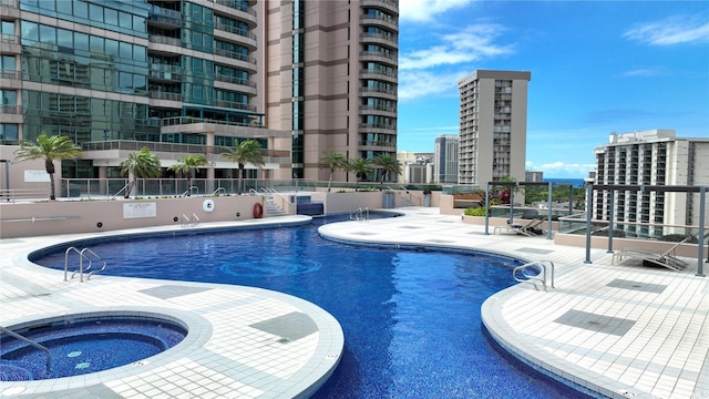 community pool with a city view, a community hot tub, and a patio area