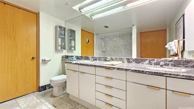 bathroom with marble look tile flooring, toilet, a tile shower, and double vanity