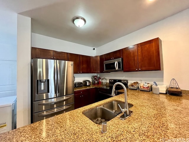 kitchen featuring stainless steel appliances, a sink, and light stone counters