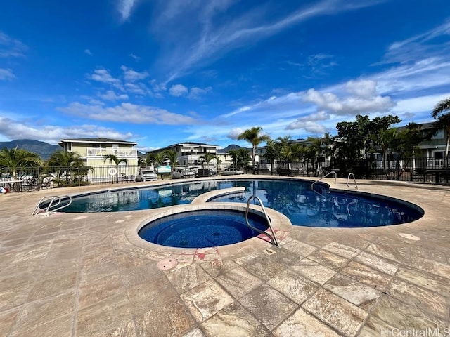 community pool featuring a hot tub, a patio area, and fence