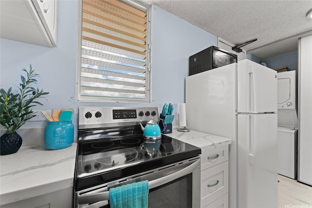 98-099 Uao Pl Unit 2408, Aiea, HI 96701 - kitchen with stacked washing machine and dryer, stainless steel electric range, light stone counters, white cabinetry, and a textured ceiling