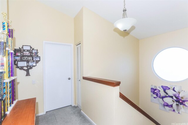 hallway featuring an upstairs landing, baseboards, and carpet floors