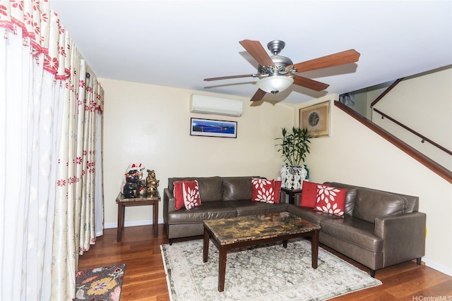 living room with a wall mounted AC, wood finished floors, baseboards, and a ceiling fan