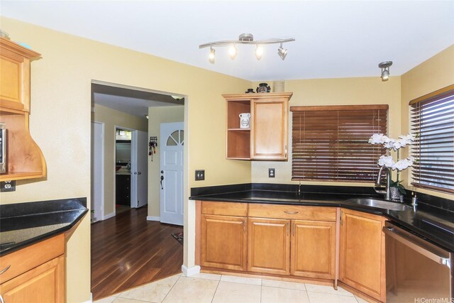 kitchen with dishwasher, a sink, dark countertops, open shelves, and light tile patterned flooring