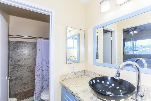 bathroom featuring toilet, a shower with curtain, vanity, and ceiling fan