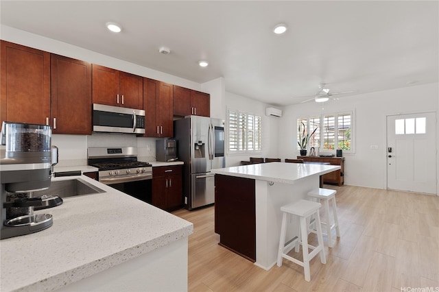 91-1139 Iliahialoe Loop, Ewa Beach, HI 96706 - kitchen featuring appliances with stainless steel finishes, a breakfast bar area, a wall unit AC, a ceiling fan, and a center island