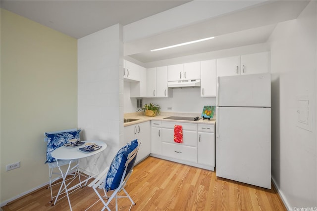 kitchen featuring freestanding refrigerator, light wood finished floors, under cabinet range hood, white cabinetry, and light countertops