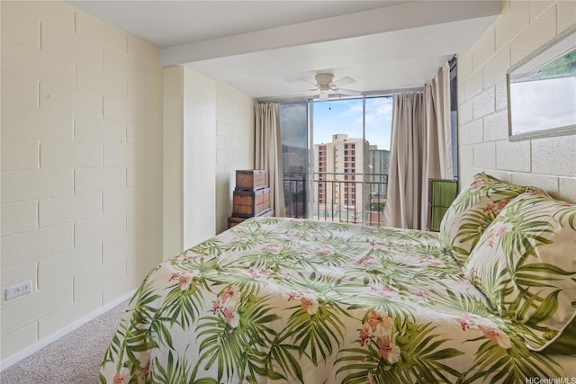 carpeted bedroom featuring concrete block wall and a ceiling fan