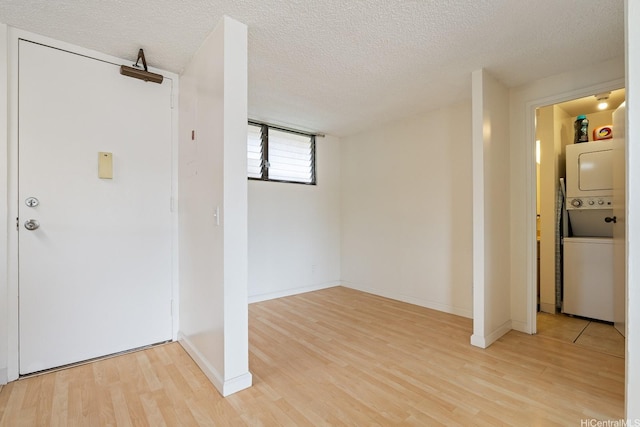entryway with estacked washer and dryer, light wood-style floors, a textured ceiling, and baseboards