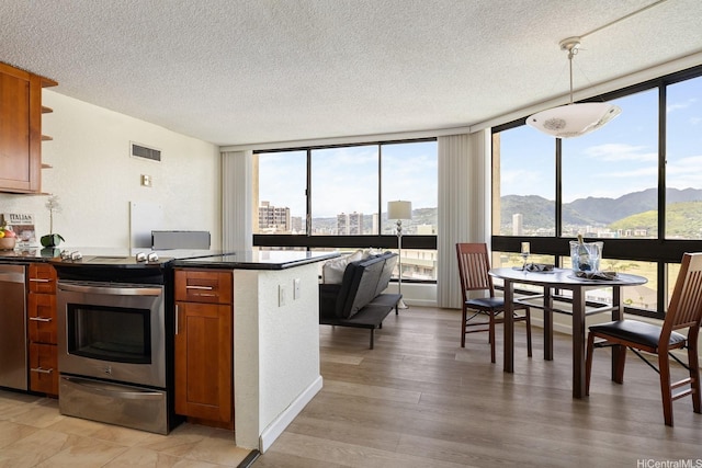 300 Wai Nani Way Unit 1902, Honolulu, HI 96815 - kitchen featuring stainless steel appliances, dark countertops, brown cabinetry, a peninsula, and expansive windows