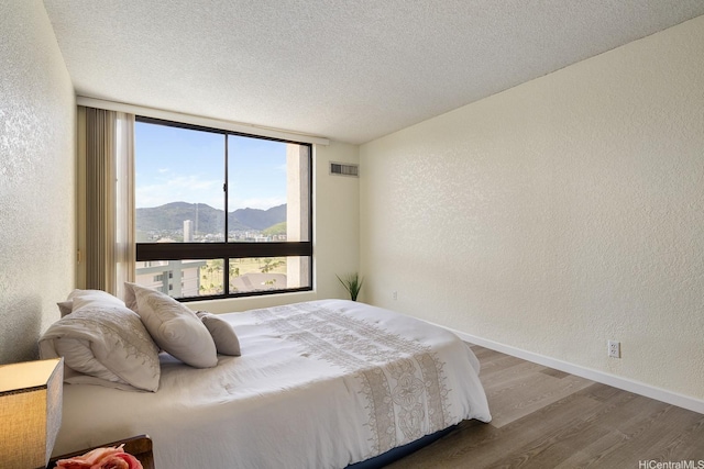 300 Wai Nani Way Unit 1902, Honolulu, HI 96815 - bedroom with a textured wall, expansive windows, wood finished floors, a mountain view, and baseboards