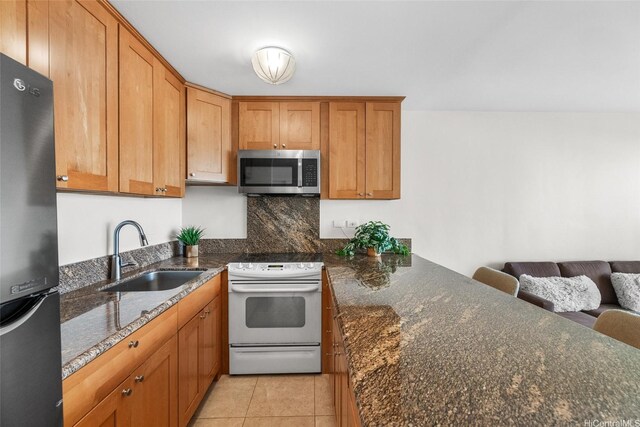 kitchen with stainless steel microwave, white range with electric cooktop, a sink, freestanding refrigerator, and a peninsula