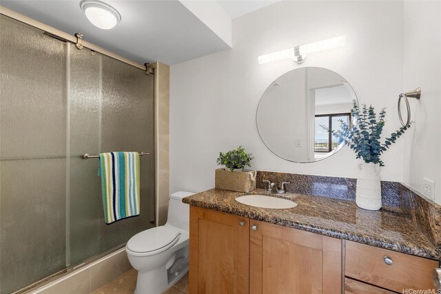bathroom featuring toilet, vanity, and a stall shower
