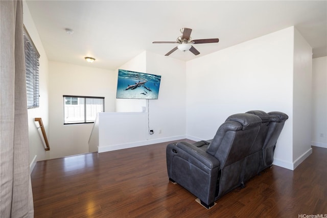 living area with an upstairs landing, wood finished floors, a ceiling fan, and baseboards