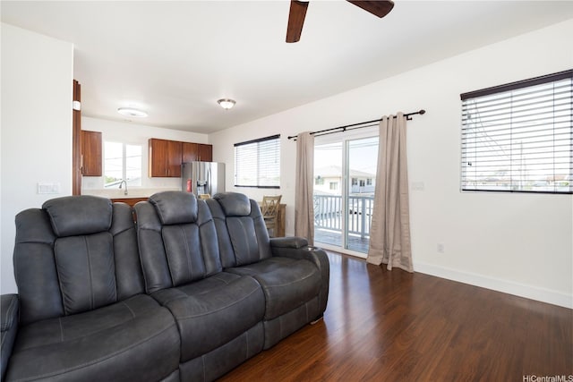 living area featuring dark wood-style flooring, ceiling fan, and baseboards