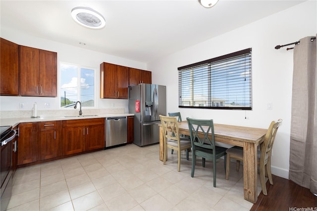 kitchen featuring stainless steel appliances, a sink, and light countertops