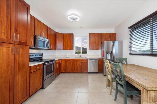 kitchen with stainless steel appliances, a sink, light countertops, and brown cabinets
