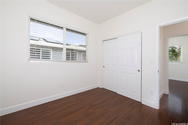 unfurnished bedroom with dark wood-style floors, baseboards, and a closet