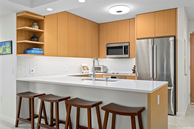 1388 Kapiolani Blvd Unit 2702, Honolulu, HI 96814 - kitchen featuring appliances with stainless steel finishes, a peninsula, a kitchen breakfast bar, tasteful backsplash, and light countertops