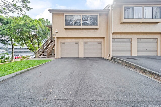 46-010 Aliikane Pl Unit 211, Kaneohe, HI 96744 - view of front of property with driveway, stucco siding, an attached garage, and stairs