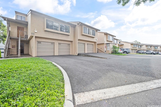 46-010 Aliikane Pl Unit 211, Kaneohe, HI 96744 - view of property featuring stucco siding, stairway, a garage, driveway, and a residential view