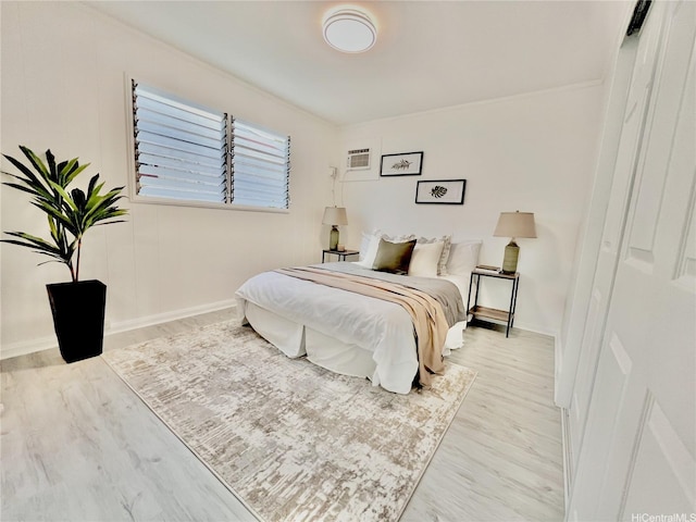 bedroom with wood finished floors, an AC wall unit, crown molding, and baseboards