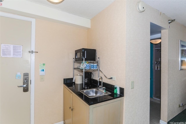 444 Kanekapolei St Unit 507, Honolulu, HI 96815 - bar area featuring a sink, black microwave, a textured ceiling, light tile patterned floors, and baseboards