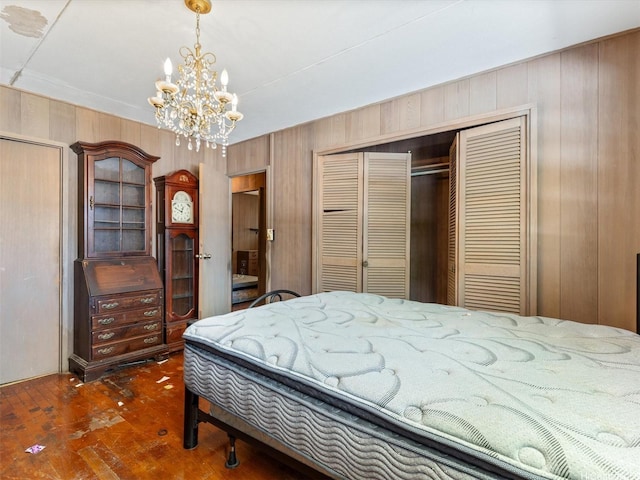 bedroom featuring a closet, hardwood / wood-style floors, a chandelier, and wooden walls