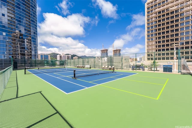 view of tennis court featuring community basketball court and fence