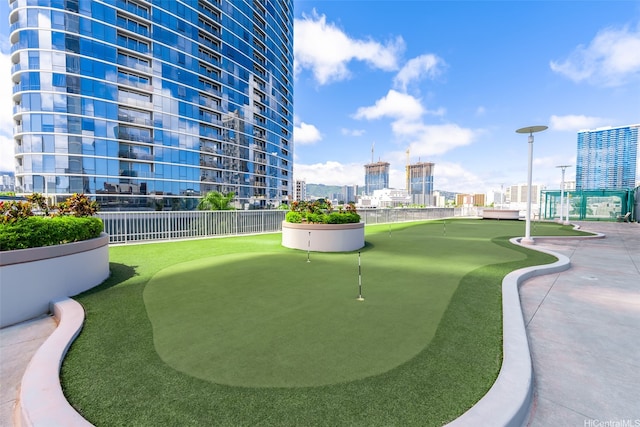 view of home's community with a city view, a putting green, and fence