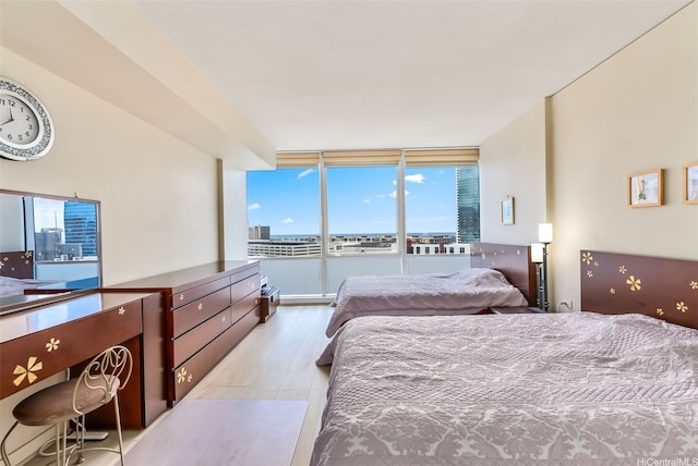 bedroom with floor to ceiling windows and light wood-type flooring