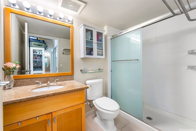 full bathroom with a stall shower, toilet, vanity, and tile patterned floors