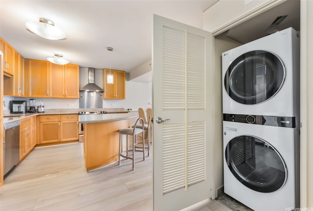 laundry room with estacked washer and dryer and light wood finished floors