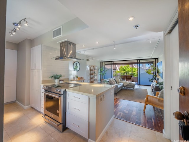 kitchen with electric range, rail lighting, island exhaust hood, white cabinets, and recessed lighting