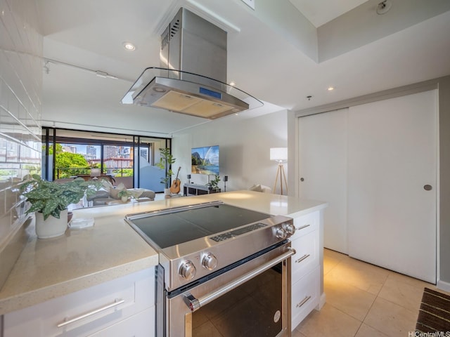 kitchen featuring stainless steel electric range, island range hood, white cabinetry, light tile patterned flooring, and recessed lighting