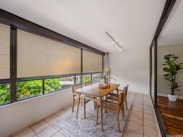 dining space with light tile patterned floors, rail lighting, and a textured ceiling
