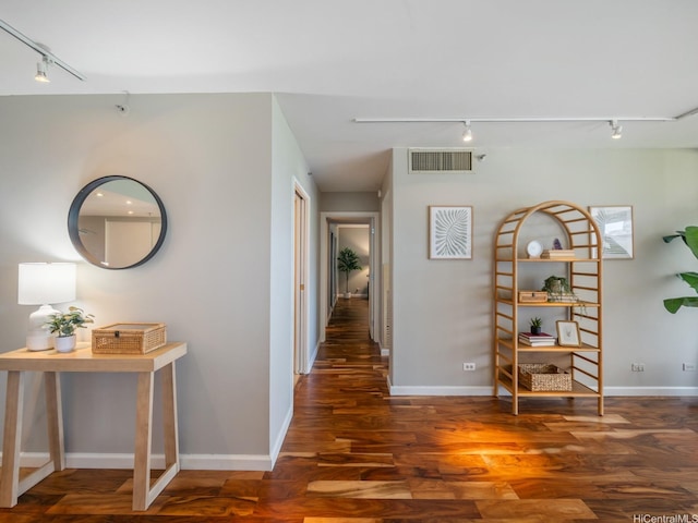 hallway with track lighting, wood finished floors, and baseboards