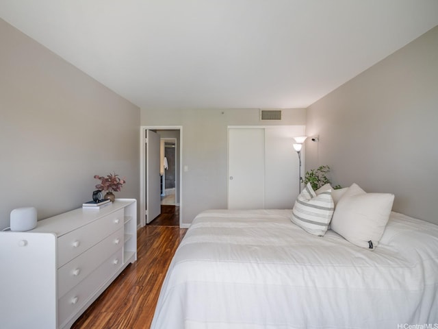 bedroom with dark wood-style floors and a closet