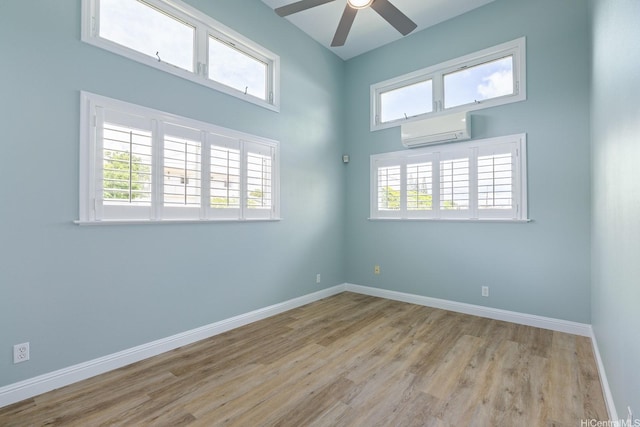 empty room featuring a wall mounted air conditioner, wood finished floors, a ceiling fan, and baseboards