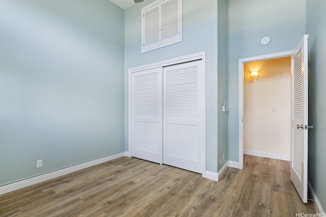 unfurnished bedroom with wood finished floors, a closet, and baseboards