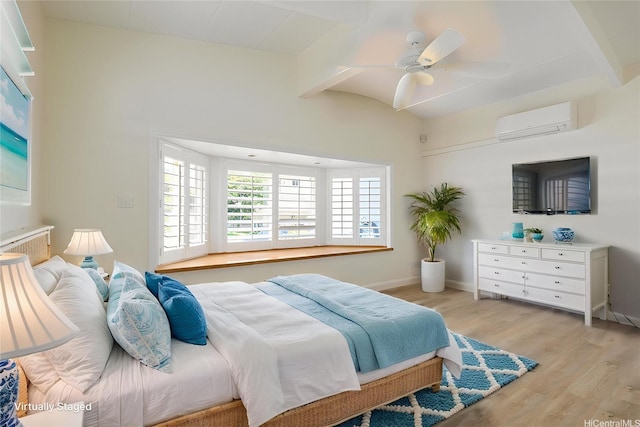 bedroom featuring a wall mounted AC, light wood-type flooring, baseboards, and a ceiling fan