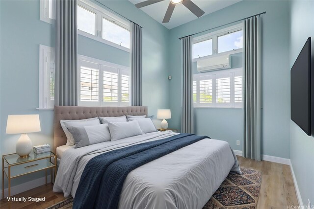 bedroom featuring an AC wall unit, baseboards, and light wood-style floors