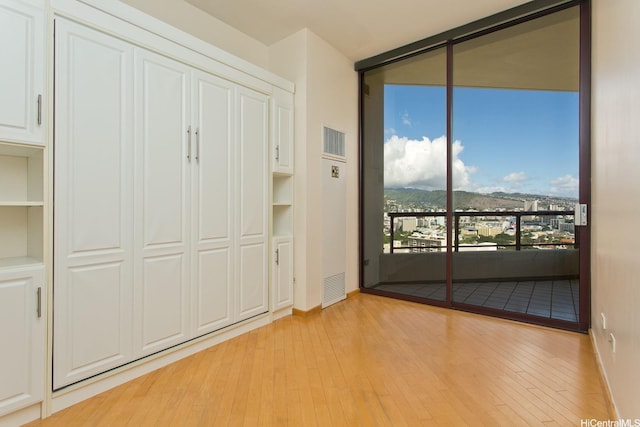 725 Kapiolani Blvd Unit 2901, Honolulu, HI 96813 - unfurnished bedroom featuring light wood-style flooring, access to exterior, a wall of windows, baseboards, and a mountain view