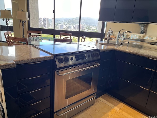 kitchen featuring stainless steel electric stove, blue cabinets, light tile patterned flooring, a city view, and modern cabinets