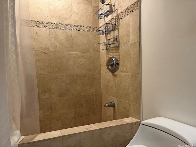 bathroom with a tile shower and toilet